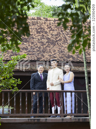 a happy groom is posing with his parents in a balcony 32090409