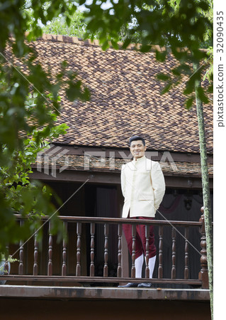 A groom is standing and smiling in the balcony. A groom is standing and smiling in the balcony. 32090435