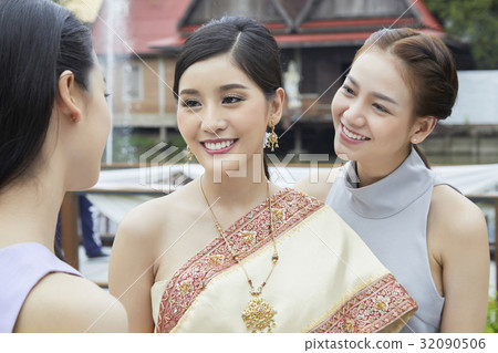 The bride and bridesmaid are looking and smiling with the other people 32090506