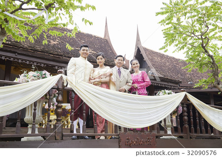 A married couple and parents are standing smiling on a balcony. 32090576