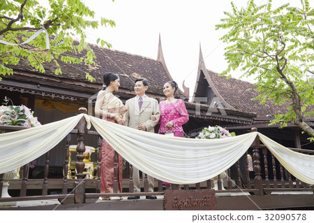 A bride is standing, smiling and looking her parents on a balcony. 32090578