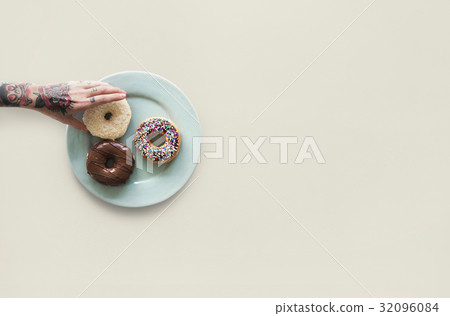 Hand with tattoo reaching for donut Hand with tattoo reaching for donut 32096084