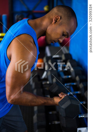 Athlete exercising with dumbbell in fitness studio Athlete exercising with dumbbell in fitness studio 32099384