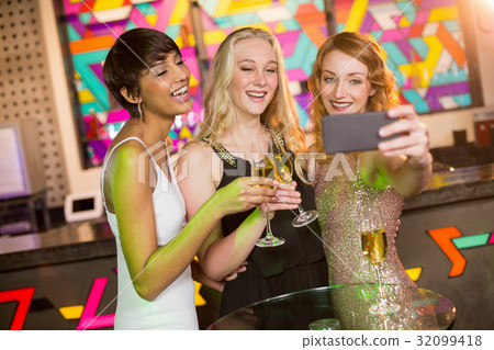 Female friends taking selfie from mobile phone while having champagne Female friends taking selfie from mobile phone while having champagne 32099418