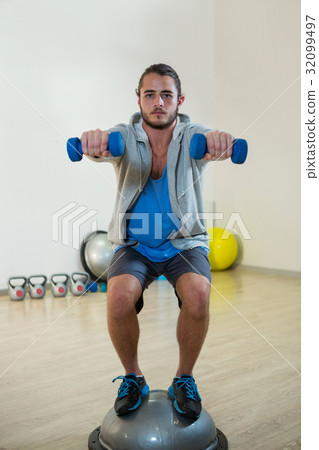 Man exercising with dumbbells on bosuball Man exercising with dumbbells on bosuball 32099497