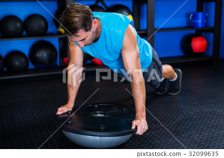 Young man with BOSU ball in gym Young man with BOSU ball in gym 32099635
