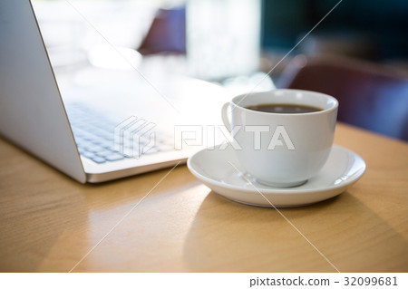 Close -up of cup of coffee and laptop on table 32099681