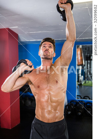 Shirtless athlete exercising with kettlebells 32099682