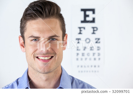 Man wearing contact lens with eye chart in background 32099701