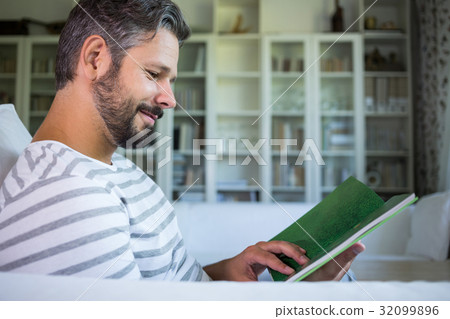 Father looking at photo album in living room 32099896
