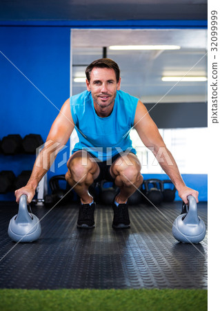 Portrait of smiling athlete with kettlebell in gym Portrait of smiling athlete with kettlebell in gym 32099999