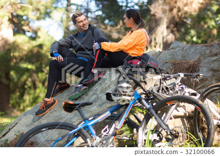 Biker couple interacting with each other in forest 32100066