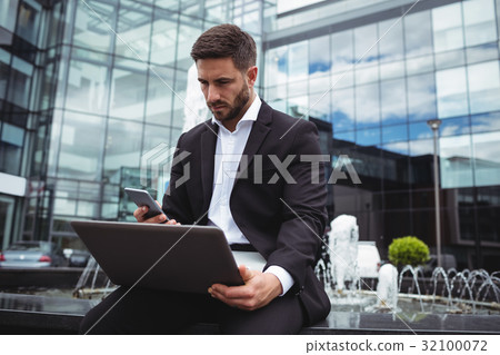 Businessman using mobile phone and laptop 32100072