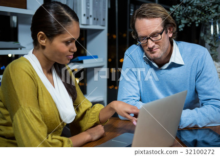 Business executives discussing over laptop Business executives discussing over laptop 32100272