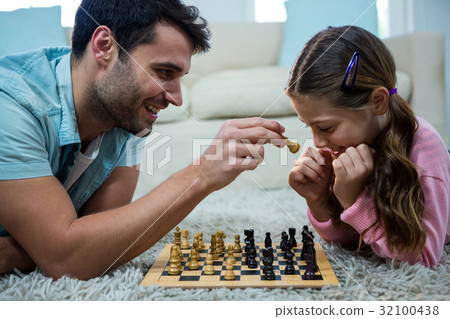 Father and daughter playing chess in the living room 32100438