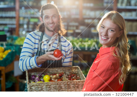 Male staff assisting woman in selecting fresh vegetables 32100447