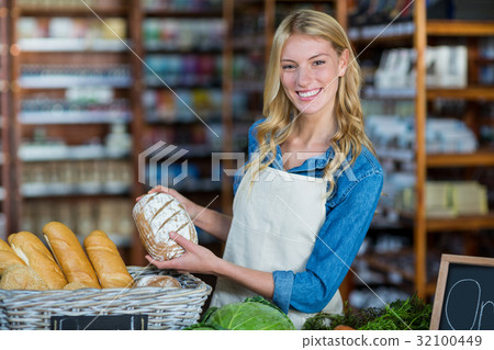 Smiling staff holding bread in organic section 32100449