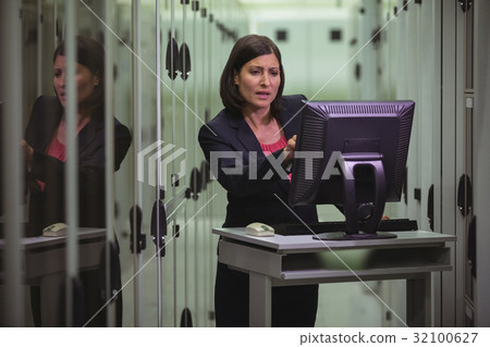 Technician working on personal computer while analyzing server 32100627