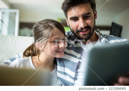 Father and daughter using laptop and digital tablet in the living room Father and daughter using laptop and digital tablet in the living room 32100640