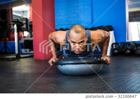 Portrait of stern male athlete with BOSU ball in gym Portrait of stern male athlete with BOSU ball in gym 32100647