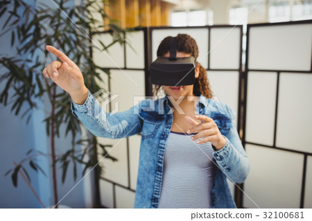 Businesswoman pointing while using virtual reality headset 32100681