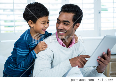 Father showing digital tablet to son on the bed 32100766