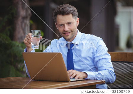 Handsome businessman having drink while using laptop 32100769