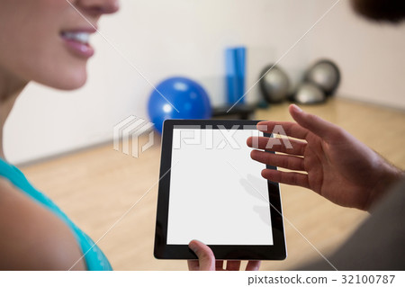 Fitness trainer showing digital tablet to woman Fitness trainer showing digital tablet to woman 32100787