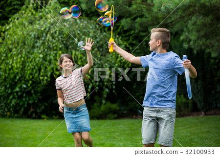 Kids playing with bubbles in the park 32100933