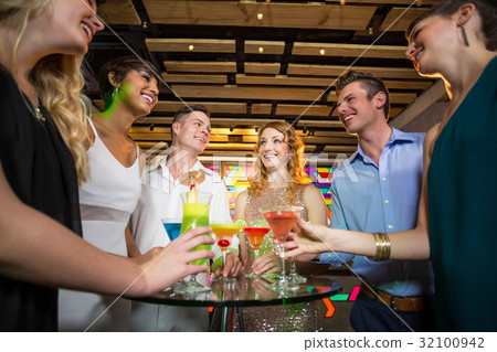 Group of friends interacting with each other while having cocktail 32100942