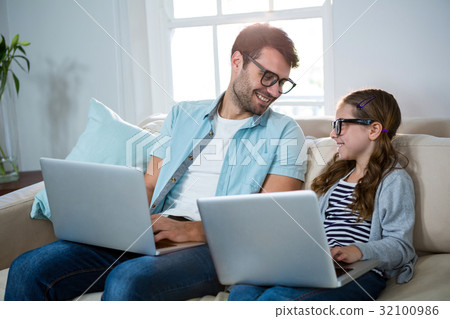 Father and daughter using laptop in the living room 32100986