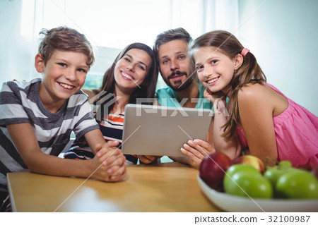 Portrait of smiling family using digital tablet while sitting at table 32100987