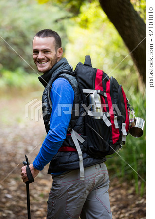 Smiling male hiker walking with hiking pole Smiling male hiker walking with hiking pole 32101010