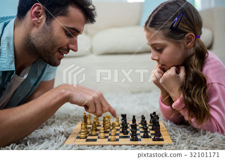 Father and daughter playing chess in the living room 32101171