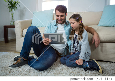 Father and daughter using digital tablet in the living room 32101174