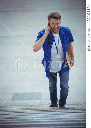 Handsome man walking on stairs while talking on mobile phone Handsome man walking on stairs while talking on mobile phone 32101194