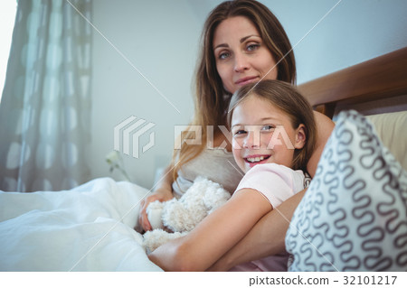 Mother lying with daughter on bed Mother lying with daughter on bed 32101217