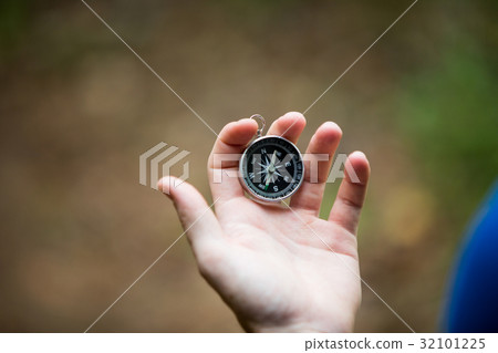 Hand holding compass in forest 32101225