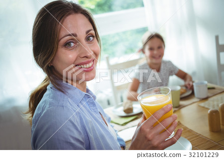 Woman having a glass of orange juice at home 32101229