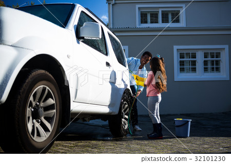 Father and daughter washing car together 32101230