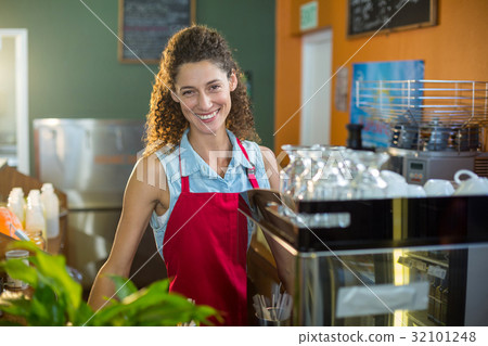 Portrait of smiling female staff standing at coffee shop counter Portrait of smiling female staff standing at coffee shop counter 32101248