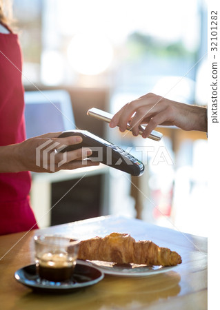 Man paying bill through smartphone using NFC technology Man paying bill through smartphone using NFC technology 32101282