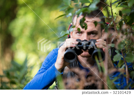 Male hiker looking through binoculars Male hiker looking through binoculars 32101429