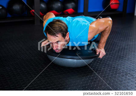 Serious man using BOSU ball in gym Serious man using BOSU ball in gym 32101650
