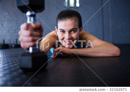 Happy female athlete holding dumbbell 32102071