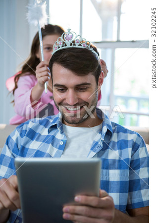 Girl dressed up in a fairy costume placing tiara on fathers head 32102245