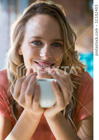 Portrait of smiling woman holding a coffee cup 32102403