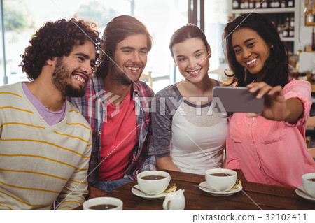 Group of friends taking a selfie while having cup of coffee 32102411