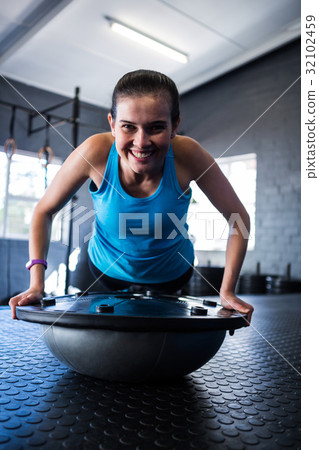 Smiling athlete with BOSU ball in gym Smiling athlete with BOSU ball in gym 32102459