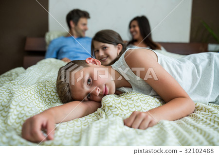 Family lying on bed in bedroom 32102488